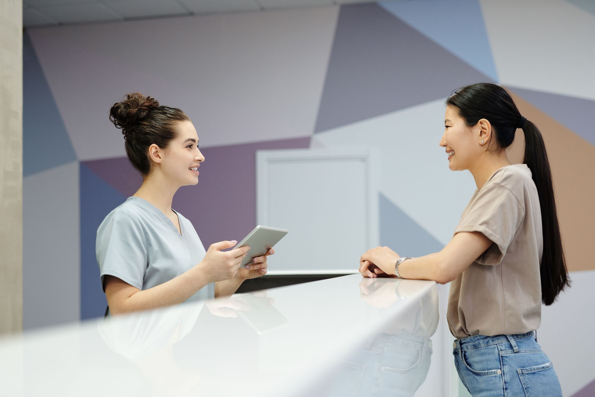 two women talking at a clinic reception desk